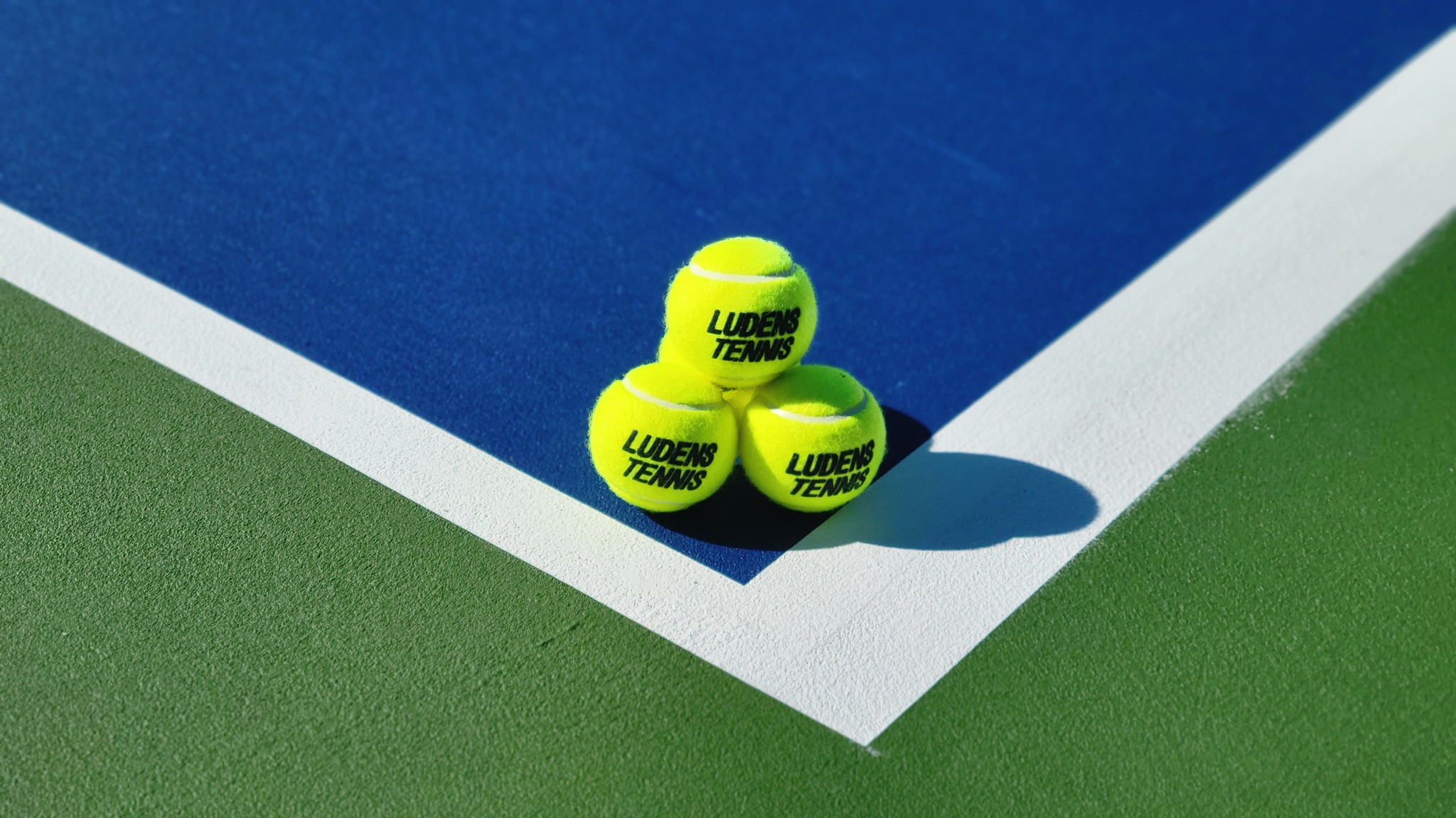 新しいコートの白いラインに並ぶLUDENS TENNISのテニスボール